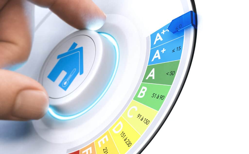 Main ajustant un thermostat intelligent avec icône de maison/thermomètre. Le cadran indique le classement énergétique A++ (<0) à G, visant l'efficacité.